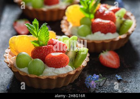 Leckere Mini-Tarte mit verschiedenen Früchten. Süßes Sommerdessert. Tarte mit Creme und Früchten. Stockfoto