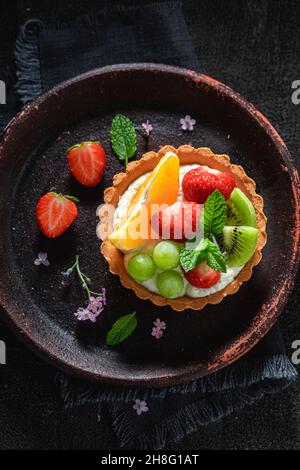 Mini-Tarte mit Erdbeeren und Trauben. Süßes Sommerdessert. Tarte mit Creme und Früchten. Stockfoto