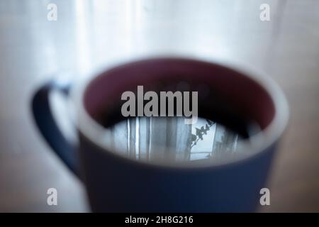 Volle Tasse Kaffee mit Spiegelung des Fensters auf der Oberfläche Stockfoto