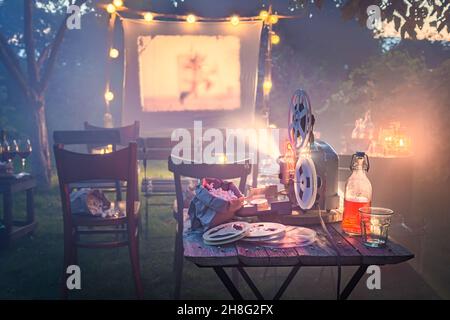 Gemütliches Sommerkino mit Vintage-Projektor im kleinen Garten Sommerkino im heimischen Garten. Stockfoto