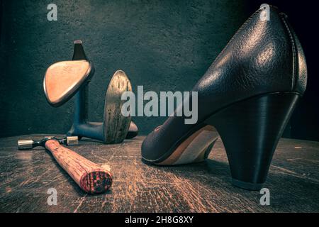 Antiker Schuster-Arbeitsplatz mit Werkzeugen, Schnürsenkeln und Schuhen. Antiker Schuster-Arbeitsplatz Stockfoto