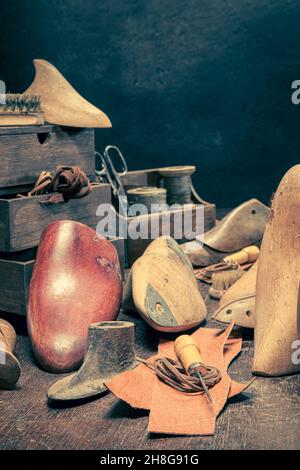 Antiker Schuster-Arbeitsplatz mit Werkzeugen, Amboss, Schuhen und Regel. Antiker Schuster-Arbeitsplatz Stockfoto