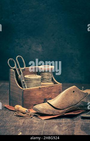 Antiker Schuster-Arbeitsplatz mit Werkzeugen, Riemen, Leder und Regeln. Antiker Schuster-Arbeitsplatz Stockfoto