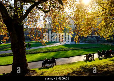 In den Victoria Embankment Gardens sitzen Menschen auf Bänken Stockfoto
