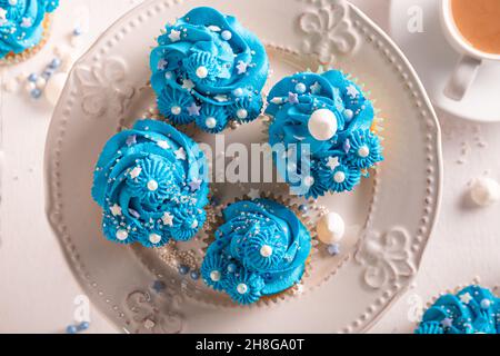 Schöne blaue Cupcakes mit blumenförmiger Creme. Blaue Cupcakes mit Kaffee. Stockfoto