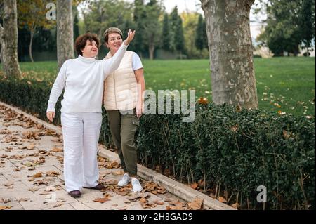 Zwei ältere Frauen im Freien. Zwei elderige Frau im Gespräch. Zwei alte Freunde unterhalten sich im Park. Lächelnde Frauen mittleren Alters sprechen draußen Stockfoto