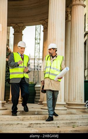 Zwei Bauarbeiter gehen und sprechen miteinander Stockfoto