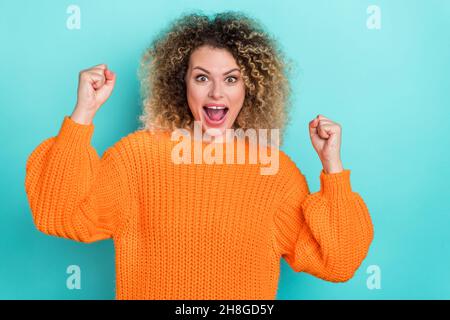 Foto von erstaunt lustige Dame feiern Sieg tragen orange gestrickt Pullover isoliert türkis Farbe Hintergrund Stockfoto