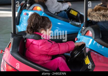 MADRID, SPANIEN - 20. Nov 2021: Glückliches Mädchen, das sich in den Autos eines Vergnügungsparks in Madrid, Spanien, amüsiert Stockfoto