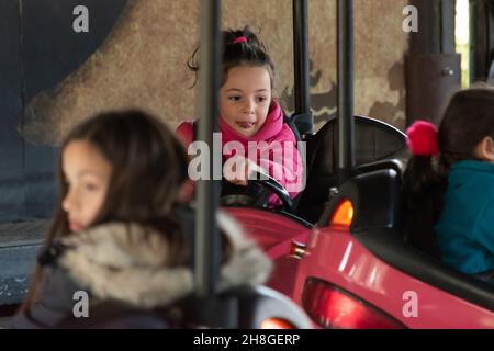 MADRID, SPANIEN - 20. Nov 2021: Glückliches Mädchen, das sich in den Autos eines Vergnügungsparks in Madrid, Spanien, amüsiert Stockfoto