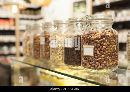 Reihe von Gläsern mit Erdnüssen und Samen im Supermarkt. Bio-Food-Konzept. Nahaufnahme Stockfoto
