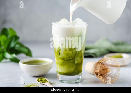Sojamilch in Matcha-Eistee gießen. Gesundes veganes Getränk Stockfoto