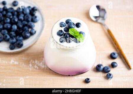 Heidelbeerjoghurt im Glas auf Holztisch. Gesunde Milchkost reich an Kalzium und Vitaminen Stockfoto