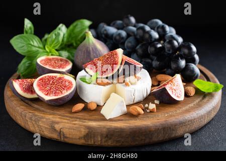 Camembert Käseplatte mit Feigen, Trauben und Nüssen. Käseplatte aus Holz Stockfoto