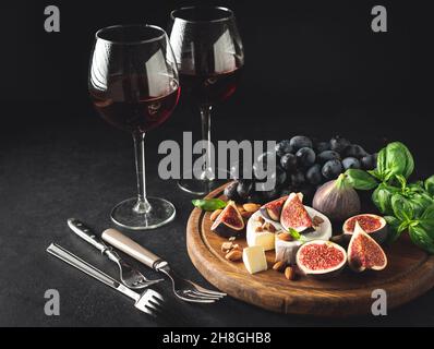 Gourmet-Vorspeise mit Wein und Käse, serviert mit Camembert und Feigen. Dunkles Bild, Kopierbereich. Stillleben Stockfoto