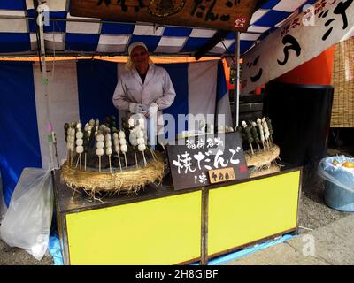 Japanische alte Männer Verkäufer Koch Kochen und Verkauf Snack Dango für japanische Knödel süß aus Mochiko auf dem Straßenmarkt Festival Altstadt in der Nähe von Fushi Stockfoto