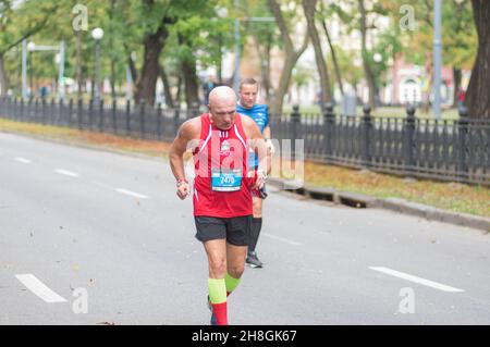 DNIPRO, UKRAINE - 26. SEPTEMBER 2021: Leitender Mann auf einer leeren Stadtstraße während der 21 km langen Strecke des Dnipro-Marathons der Almaz-Gruppe Stockfoto