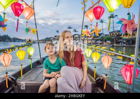 Glückliche Familie Mutter und Sohn von Reisenden reiten auf einem Nationalboot auf dem Hintergrund der alten Stadt Hoi, Vietnam. Vietnam öffnet sich danach wieder für Touristen Stockfoto