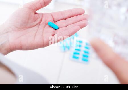 Kaukasisches weibliches Model hält Pille und Glas Wasser in ihren Händen Stockfoto