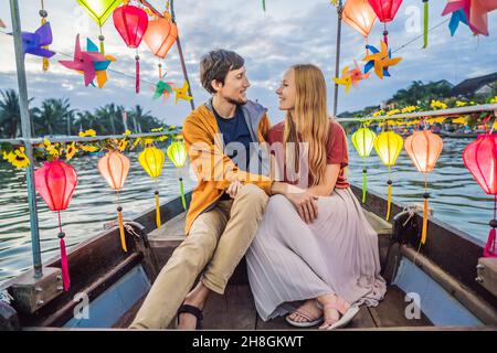 Ein glückliches Paar von Reisenden fährt auf einem Nationalboot auf dem Hintergrund der alten Stadt Hoi in Vietnam. Vietnam öffnet sich nach der Quarantäne wieder für Touristen Stockfoto
