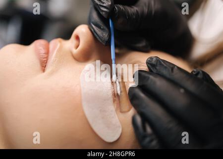 Nahaufnahme der Wimpern Pflege Behandlungsverfahren. Schöne weibliche, blonde Haar-Modell haben Wimpern Laminierung. Frau beim Färben, Locken, Laminieren Stockfoto