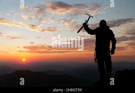 Abendsilhouette - Blick auf den Menschen auf den Bergen mit Eis axt in der Hand Stockfoto