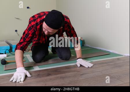 Werkmann installiert Laminat. Reparatur der Wohnung, Verlegung Laminatboden Stockfoto