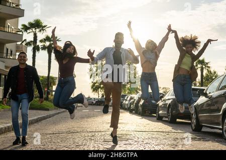 Eine Gruppe junger Menschen, die in einer Stadtstraße springen und lachen, fröhliche Studenten, die die erzielten Erfolge feiern Stockfoto