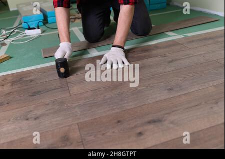 Werkmann installiert Laminat. Reparatur der Wohnung, Verlegung Laminatboden Stockfoto