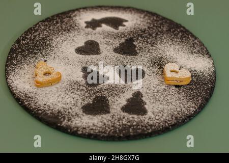 Weihnachtskekse in verschiedenen Formen in Zuckerglasur auf dunklem Teller mit Zucker bestreut, flach legen.Weihnachtskomposition mit traditionellen Linzer Christma Stockfoto