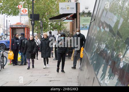 London, Großbritannien, 30. November 2021: Käufer sind nun gesetzlich verpflichtet, in Geschäften oder öffentlichen Verkehrsmitteln eine Gesichtsmaske zu tragen. In der Clapham High Street Filiale des Sainsbury's Supermarkts kommen und gehen die Käufer und entfernen oft ihre Masken, sobald sie draußen an die frische Luft treten. Anna Watson/Alamy Live News Stockfoto