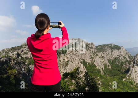 Frau, die mit dem Handy auf dem Berg fotografiert. Stockfoto