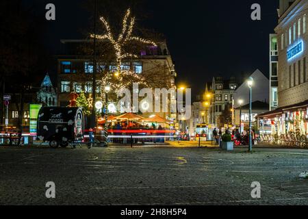 Auf dem hell erleuchteten weihnachtsmarkt vor dem bremer Theater am goetheplatz stehen Menschen Stockfoto