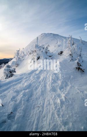 Sonnenuntergang über dem Gipfel und den verschneiten Bergen an einem wunderschönen Wintertag, Quebec, Kanada Stockfoto