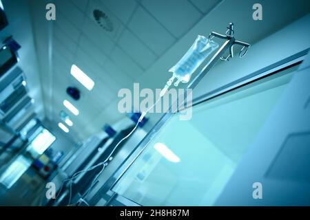 Korridor des Krankenhausgebäudes mit intravenösem Tropfsack, der an der Stahlstange hängt, medizinischer Hintergrund. Stockfoto