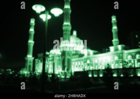 Verschwommener Blick auf die Moschee in der Nacht, unfokussierter Hintergrund. Stockfoto