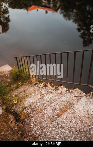 Vertikale Aufnahme der Steintreppe, die zum Fluss hinabsteigt. Stockfoto