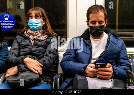 Passagiere mit Gesichtsmasken in Einem Londoner U-Bahn-Zug, London, Großbritannien. Stockfoto