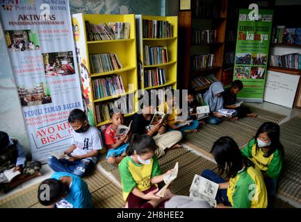 Bogor, Indonesien. 29th. November 2021. Eine Gruppe von Kindern, die am 29. November 2021 in einer Gemeinschaftsbibliothek am Fuße des Mount Salak im Dorf Sukaluyu in Bogor, West-Java, Indonesien, Bücher lesen. (Foto von Adriana Adie/INA Photo Agency/Sipa USA) Quelle: SIPA USA/Alamy Live News Stockfoto