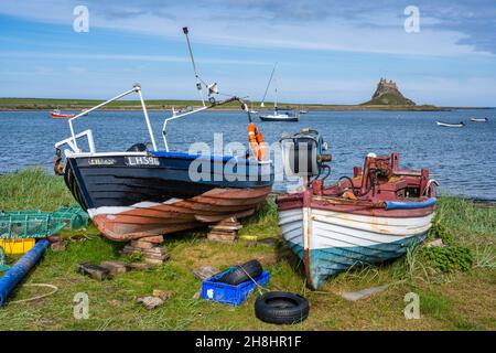 Fischerboote, die am Strand aufgestellt wurden, mit Fernsicht auf das Schloss Lindisfarne auf der Heiligen Insel an der Northumberland-Küste von England, Großbritannien Stockfoto