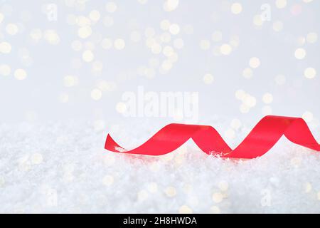 Festlicher Winterhintergrund mit einem roten Band auf dem Schnee. Stockfoto