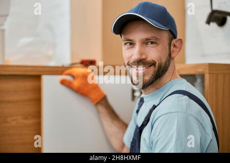 Fröhlicher männlicher Arbeiter, der die Kamera ansah und lächelte Stockfoto