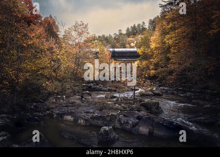 Aufgenommen in den Great Smokey Mountains in der Nähe von Gatlinburg, Tennessee. Ein wunderschöner, landschaftlich schöner Wasserweg mit wunderschönem Zugwerk über den tobenden Stromschnellen unten. Stockfoto