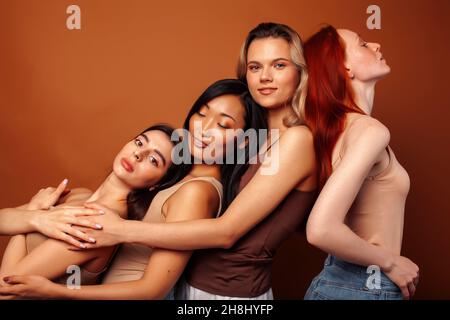 Junge hübsche kaukasische, afro, skandinavische Frau posiert fröhlich zusammen auf braunem Hintergrund, Lifestyle diverse Nationalität Menschen Konzept Stockfoto