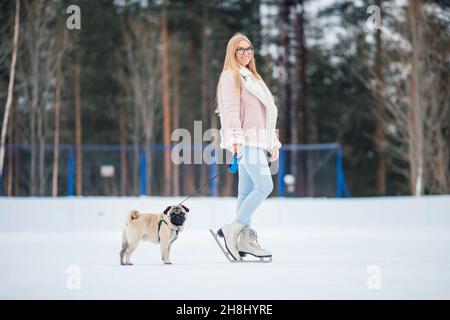 Glückliche Freunde Tiere, junge Frau geht in für Sport auf Schlittschuhen mit Mops Hund. Stockfoto