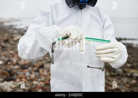 Ausgeschnittene Aufnahme eines Mannes in einem Hazmat-Anzug, der Sonden im Freien sammelt, Konzept der Industrieverschmutzung, Kopierraum Stockfoto