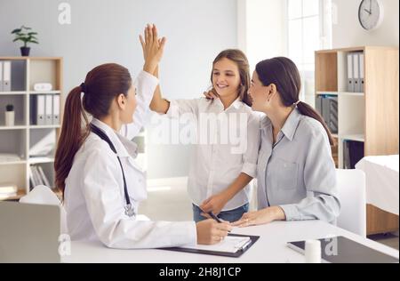 Das kleine Mädchen, das mit ihrer Mutter einen Arzt aufsucht, gibt der Ärztin bei einem Krankenhausgespräch hohe fünf. Stockfoto