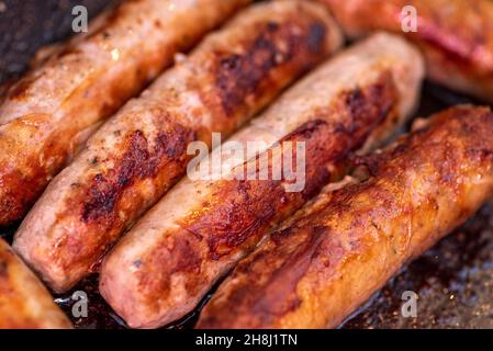 Horizontales Farbfoto von Schweinswürsten, die in einer Bratpfanne brutzeln Stockfoto