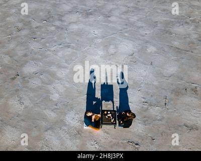 Vogelperspektive auf zwei Personen, die in der Wüste ein Picknick machen Stockfoto