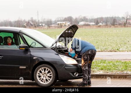 Riga, Lettland, 2. Januar 2021: Der Autofahrer füllt die blaue, nicht gefrierende Scheibenwaschflüssigkeit in den Tank des Autos Stockfoto